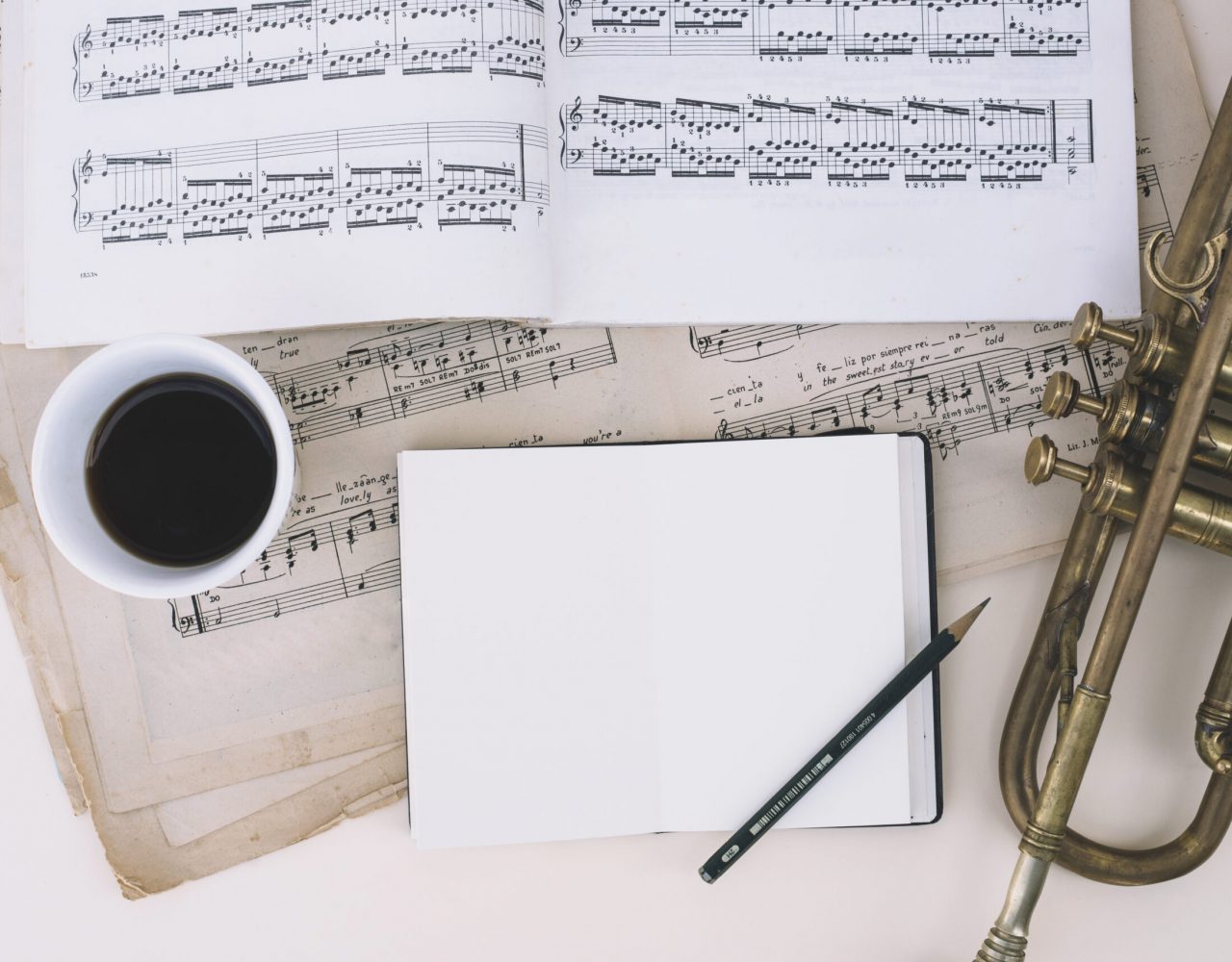 notebook-and-coffee-near-sheet-music-and-trumpet (1)